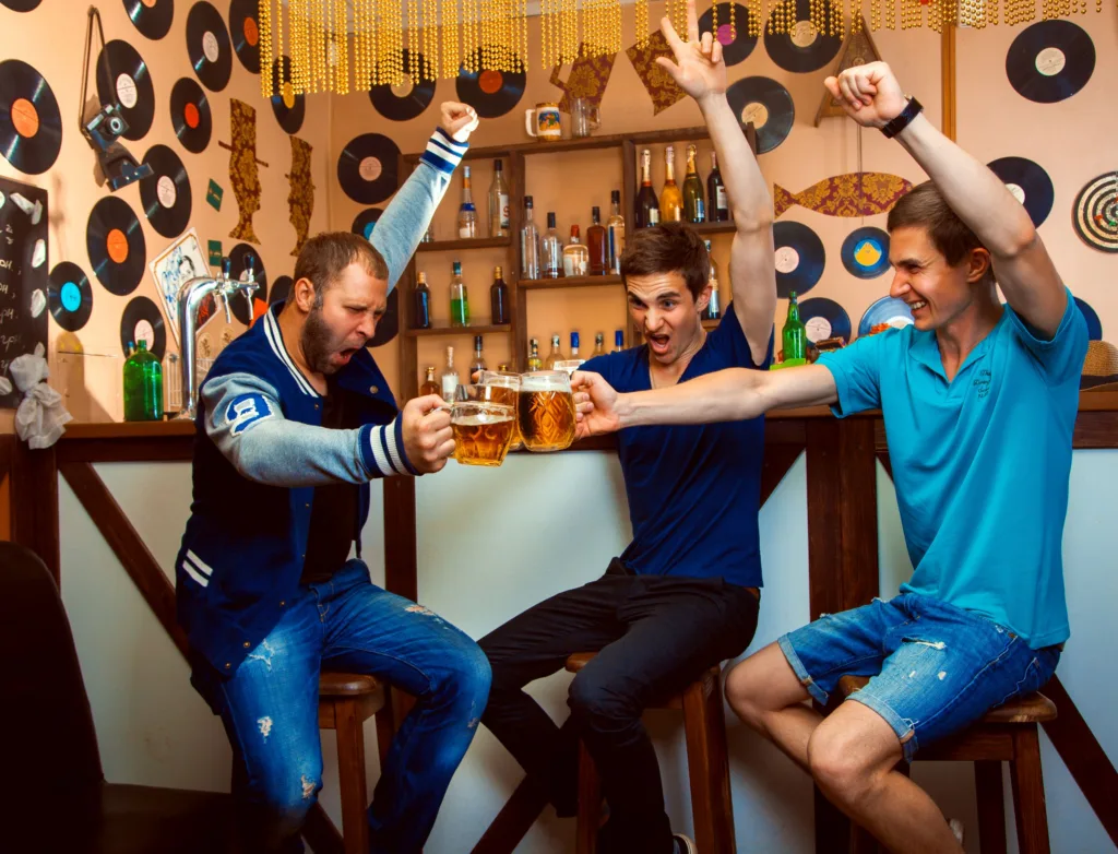 Men celebrating at a bar and clinking beer glasses