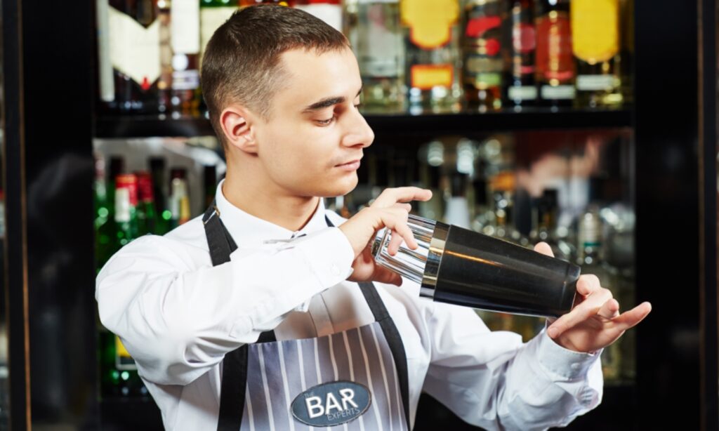 A bartender shaking a cocktail behind the bar